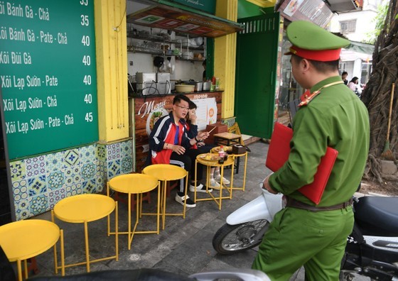 Lực lượng công an nhắc nhở một trường hợp lấn chiếm vỉa hè. Ảnh: Sài Gòn Giải phóng
