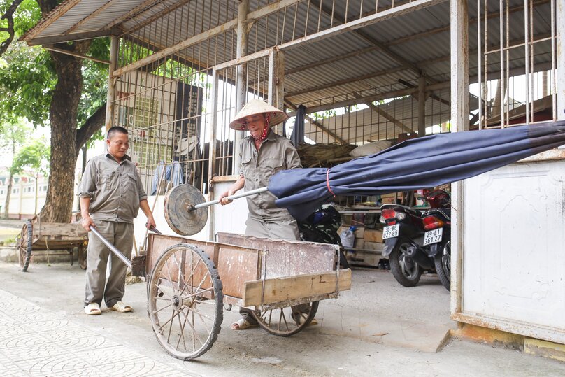 Ông Nguyễn Quốc Tiến và Nguyễn Tá Lân (người trông coi nghĩa trang) đưa những chiếc ô ra nơi tổ chức lễ tránh thời tiết thất thường làm gián đoạn buổi lễ.