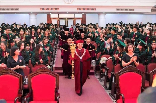  Hiệu trưởng Trường Đại học Kinh tế (Đại học Quốc gia Hà Nội) cầm cây quyền trượng, khoác áo thụng, đeo vòng cổ cùng đoàn giảng viên bước vào buổi lễ.