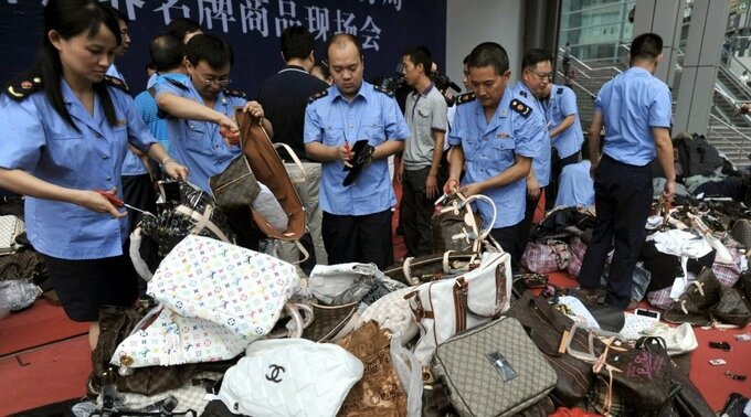 Lực lượng quản lý thị trường Trung Quốc kiểm tra túi xách giả. Ảnh: AP
