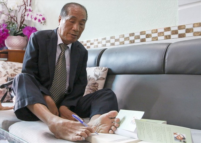 Thầy giáo Nguyễn Ngọc Ký viết chữ bằng chân. Ảnh: IT