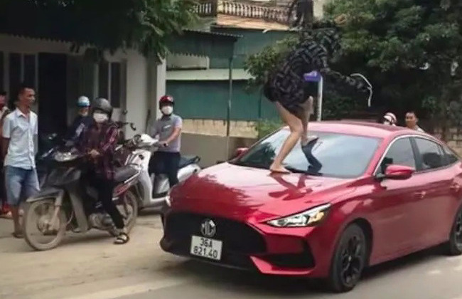 Người phụ nữ nhảy lên đầu xe ô tô, dùng chân đạp vỡ kính: Ảnh: Cắt từ clip.