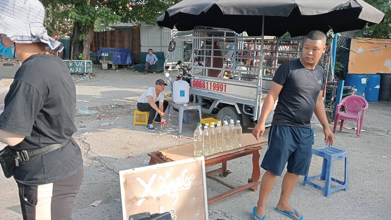 Ngay cạnh đó một số tiểu thương mang xăng từ đâu ra bày bán với giá cắt cổ, 50 nghìn đồng/chai chưa được 1 lít. Nhiều người thắc mắc không biết những tiểu thương này lấy xăng ở đâu để ra bán giữa lòng đường? Chất lượng những chai xăng này có đảm bảo không? Có an toàn về cháy nổ không? (Ảnh: Phương Nam).