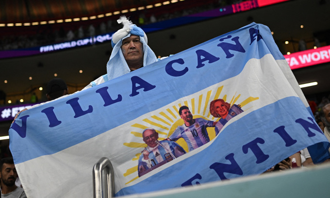 Một khán giả Argentina cầm lá cờ có hình Lionel Messi, trong sân Al Bayt. Ảnh: Reuters