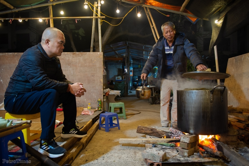 Nhiệt độ về đêm giảm sâu, tại phố Trịnh Công Sơn (quận Tây Hồ, Hà Nội), ông Tuyến cùng bạn bè đang quây quần bên bếp lửa để trông nồi bánh chưng Tết.