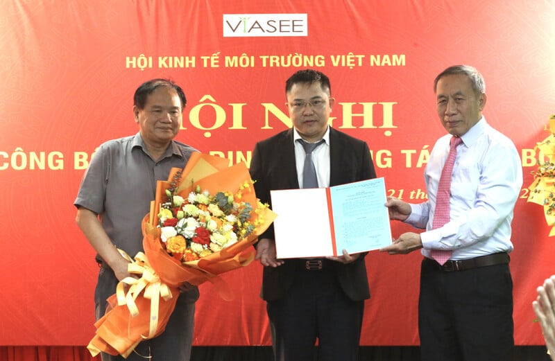 PGS.TS Lưu Đức Hải - Chủ tịch Hội Kinh tế Môi trường Việt Nam (bên phải) và PGS.TS Nguyễn Thế Chinh - Phó Chủ tịch Hội Kinh tế Môi trường Việt Nam trao quyết định bổ nhiệm Tổng biên tập và tặng hoa chúc mừng Nhà báo Nguyễn Tường Quân.