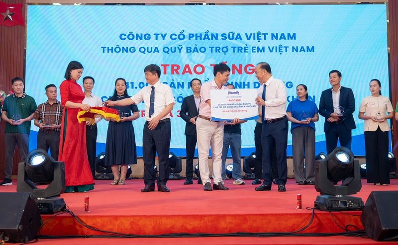 Ông Phạm Tuyên, Giám đốc chi nhánh Vinamilk Hà Nội (đứng giữa) trao bảng tượng trưng món quà 41.000 hộp sữa cho trẻ em Phú Thọ.
