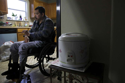 Khanh Hung Le ngồi trên xe lăn trong căn bếp ở nhà chị gái, nơi anh và con gái 7 tuổi đang nương nhờ. Ảnh: Houston Chronicle.