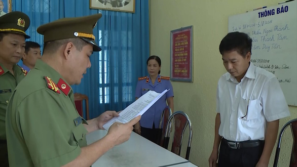 Ông Trần Xuân Yến, phó giám đốc Sở GD-ĐT tỉnh Sơn La (áo trắng), nghe tống đạt quyết định khởi tố bị can (Ảnh Tuổi Trẻ)