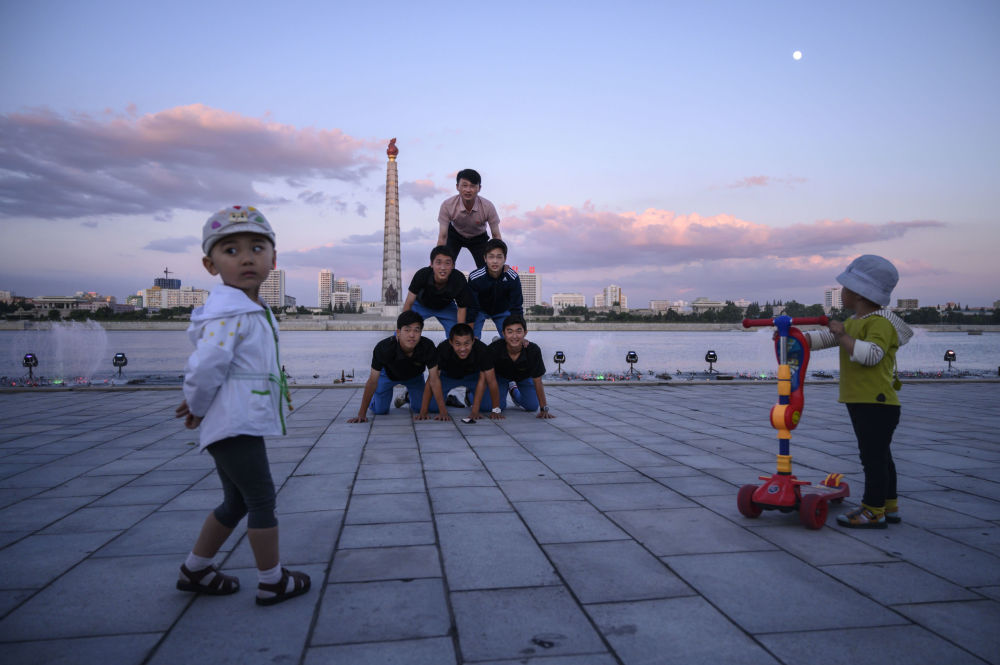 Một nhóm du khách chụp ảnh trên bờ sông Taedong, trước tòa tháp Juche nổi tiếng ở Bình Nhưỡng hôm 15/6.