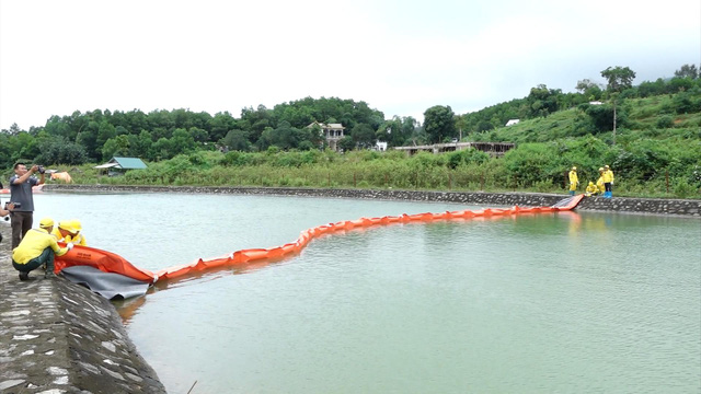 Công nhân lắp màng xử lý dầu tại khu vực kênh dẫn nước vào Nhà máy nước sạch sông Đà. (Ảnh: VTV).