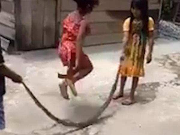 Ba em nhỏ chơi nhảy dây bằng xác rắn.