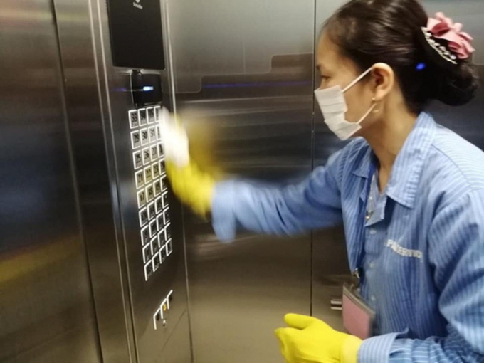 Nhân viên vệ sinh lau khu vực cầu thang máy nơi nhiều người tiếp xúc.