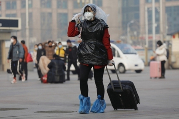 Một hành khách tại nhà ga Bắc Kinh che đầu và cơ thể bằng túi nilon để phòng ngừa virus corona. (Ảnh: EPA-EFE).