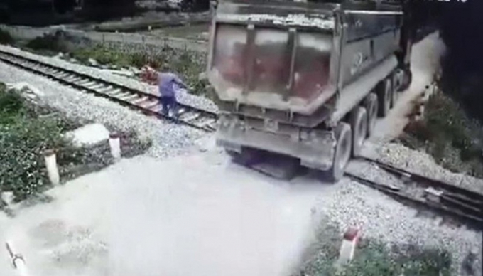 Hình ảnh nam nhân viên gác chắn chạy ngăn tàu hỏa khi chiếc xe ô tô mắc kẹt. (Ảnh: Cắt từ clip).