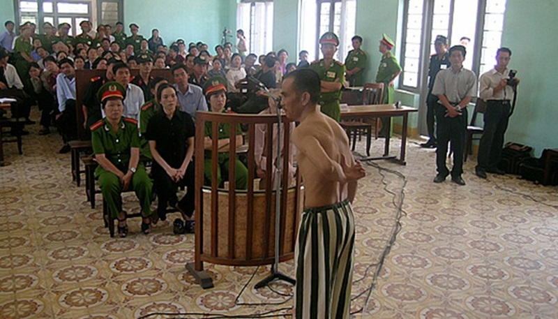 Ông Huỳnh Văn Nén cởi áo, chỉ những vết sẹo mà ông nói là do bị đánh trong tù, tại phiên tòa phúc thẩm (lần 3) “Vụ án vườn điều”. (Ảnh: Nguyễn Đình Quân).