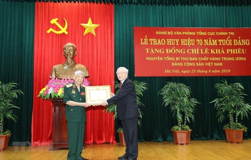 Tổng bí thư, Chủ tịch nước Nguyễn Phú Trọng trao Huy hiệu 70 năm tuổi Đảng tặng nguyên Tổng bí thư Lê Khả Phiêu. (Ảnh: TTXVN).