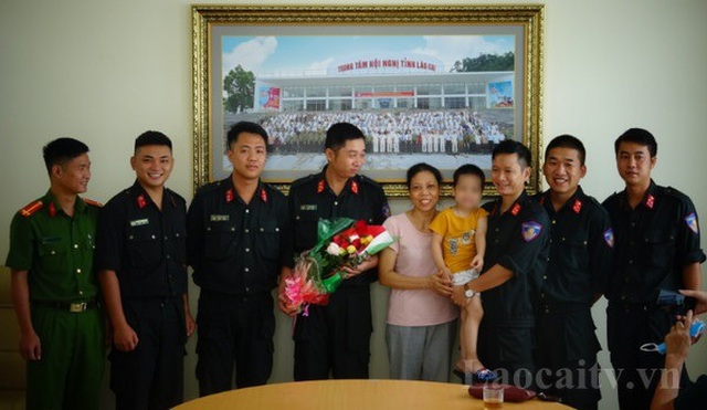 Lực lượng Công an Lào Cai bàn giao cháu bé đi lạc cho gia đình. (Ảnh: Đài PTTH Lào Cai)