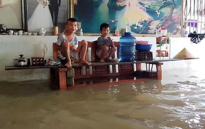 Hình ảnh hai đứa trẻ đang ngồi trên cao giữa dòng nước lũ chảy trong nhà trong đợt mưa lũ ở Quỳnh Lưu - Nghệ An.