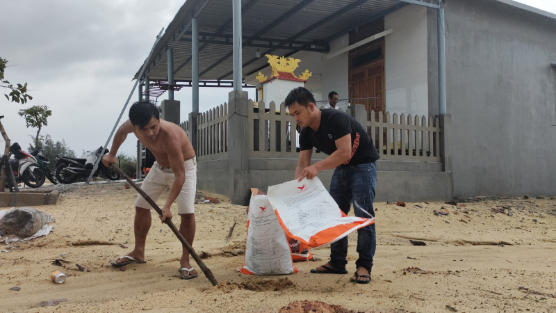 Người dân đổ cát vào bao để chèn chắn mái nhà.