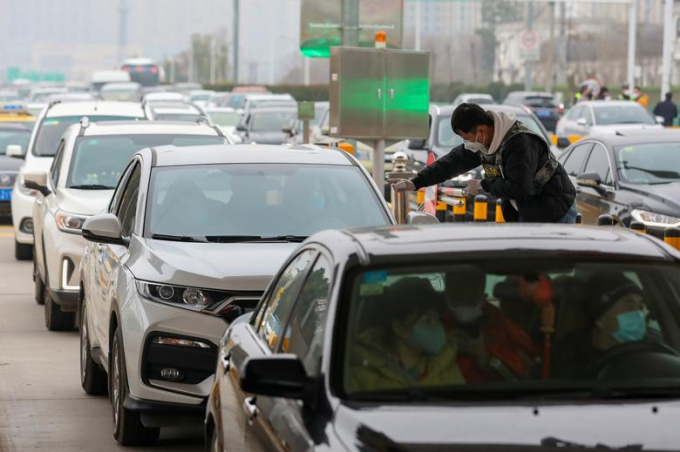 Một nhân viên của một đội vệ sinh và phòng chống dịch bệnh địa phương kiểm tra nhiệt độ của người ngồi trên xe hơi tại trạm thu phí ở Vũ Hán, tỉnh Hồ Bắc, Trung Quốc, để kiểm dịch virus corona.