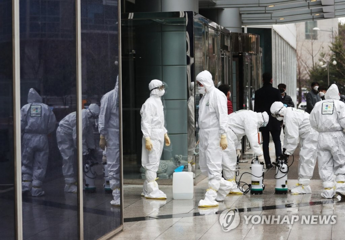 Nhân viên y tế mặc đồ bảo hộ đang sắp xếp thiết bị khử trùng tại ở Seoul hôm 25/2.