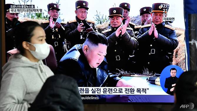 Một người phụ nữ đeo khẩu trang bước qua màn hình đưa tin về nhà lãnh đạo Triều Tiên Kim Jong Un, tại một nhà ga ở Seoul hôm 21/3/2020.