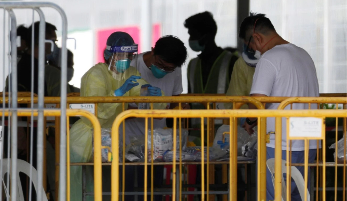 Nhân viên y tế phân loại vật tư y tế tại một ký túc xá người lao động nước ngoài ở Singapore để xét nghiệm Covid-19.