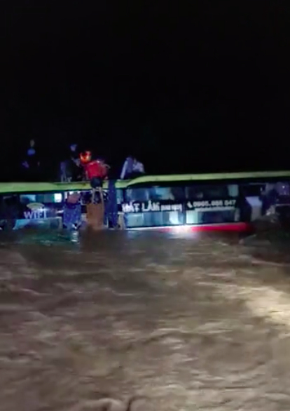 Chiếc xe khách ngập sâu dưới dòng nước lũ, bị cuốn trôi khoảng 300 m. Ảnh cắt từ clip.