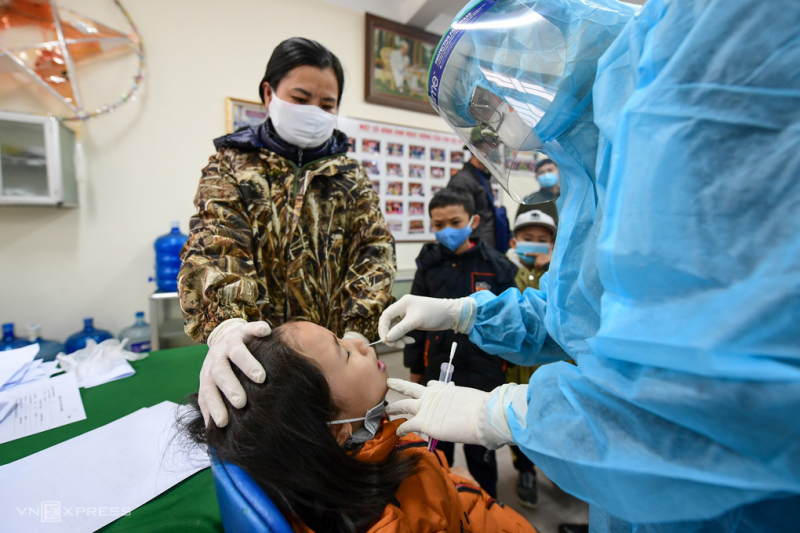 Nhân viên y tế lấy mẫu xét nghiệm cho học sinh trường Tiểu học Xuân Phương, chiều 31/1. Ảnh: Giang Huy.