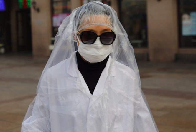 Một hành khách mặc áo nylon kín người đi bên ngoài ga tàu ở Bắc Kinh hôm 11/2. Ảnh: EPA-EFE.