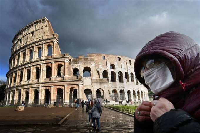 Một người đàn ông đeo mặt nạ đứng bên ngoài Đấu trường La Mã ở Rome hôm 7/3. Ảnh: AFP