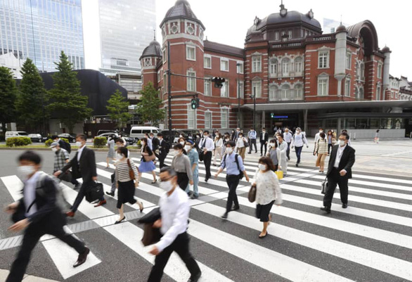 Người dân đi bộ ở bên ngoài một ga tàu điện ngầm ở Tokyo sáng 25-5, nhiều giờ trước khi chính phủ chính thức tuyên bố gỡ bỏ tình trạng khẩn cấp còn lại tại thủ đô Tokyo và 4 tỉnh. Ảnh: KYODO