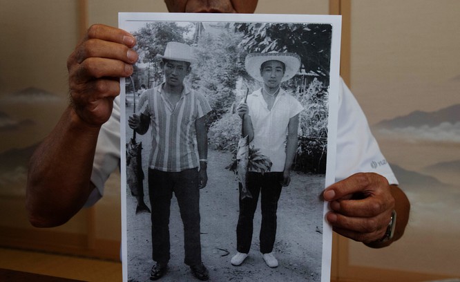 Masashi Yuri, một người bạn học của ông Suga, giơ tấm ảnh chụp hai người lúc 15 tuổi (Ảnh: Reuters)