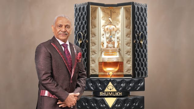 Người sáng lập và chủ tịch của Tập đoàn nước hoa Nabeel Asghar Adam Ali đứng cạnh chai 