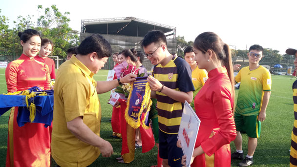 Đồng chí Nguyễn Thế Kỷ (áo vàng) trao cờ lưu niệm cho đại diện đội bóng Báo Hànộimới.  