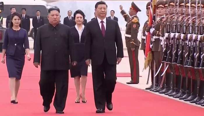Nhà lãnh đạo Triều Tiên Kim Jong Un (trái) đón Chủ tịch Trung Quốc Tập Cận Bình sang thăm ngày 20/6 - Ảnh: AP/Bloomberg.    