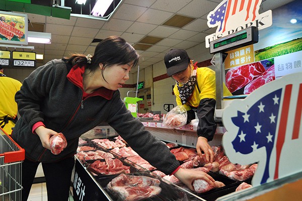 Một khách hàng đang chọn thịt heo nhập khẩu từ Mỹ tại một siêu thị ở TP Trịnh Châu, tỉnh Hà Nam, Trung Quốc Ảnh: China Daily