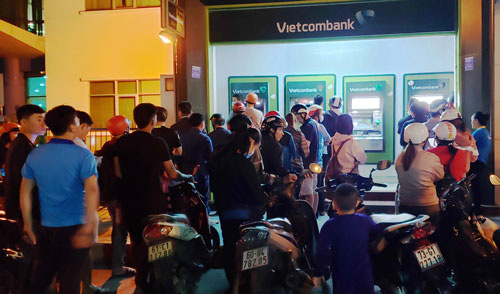Công nhân xếp hàng chờ rút tiền lương tại trụ ATM trước cổng Vietcombank (VSIP1) tối 10-12