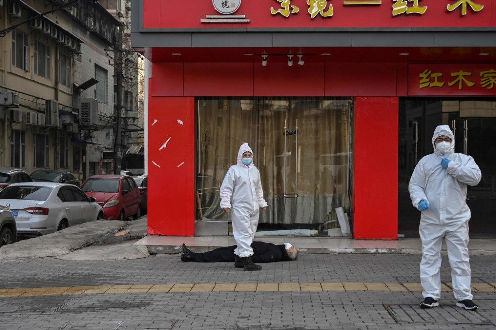     Cán bộ y tế ở nơi một người đàn ông đeo khẩu trang và chết ngay vỉa hè ở Vũ Hán. Ảnh: AFP. 