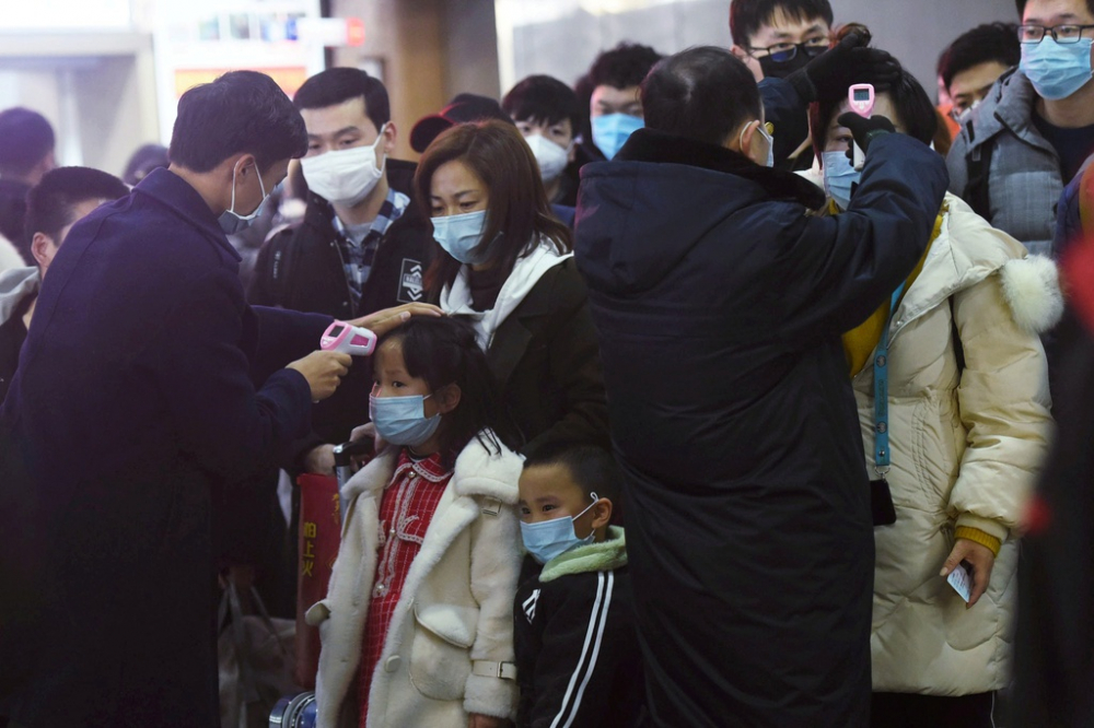     Nhân viên y tế ở Hàng Châu, Trung Quốc đo thân nhiệt hành khách đi tàu từ Vũ Hán ngày 23/1. Ảnh: China Daily/Reuters. 