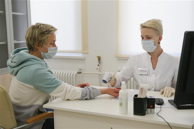 Nhân viên y tế kiểm tra thân nhiệt cho người dân trước khi tiêm vaccine ngừa COVID-19 tại Moskva, Nga ngày 5/12/2020. Ảnh: THX/TTXVN