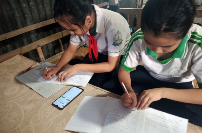 Nguyễn Thị Có, lớp 8 (phải) và em ruột Nguyễn Thị Thuỳ Linh, lớp 6, cùng học online bằng một điện thoại của cha mẹ. Ảnh: Đức Duy