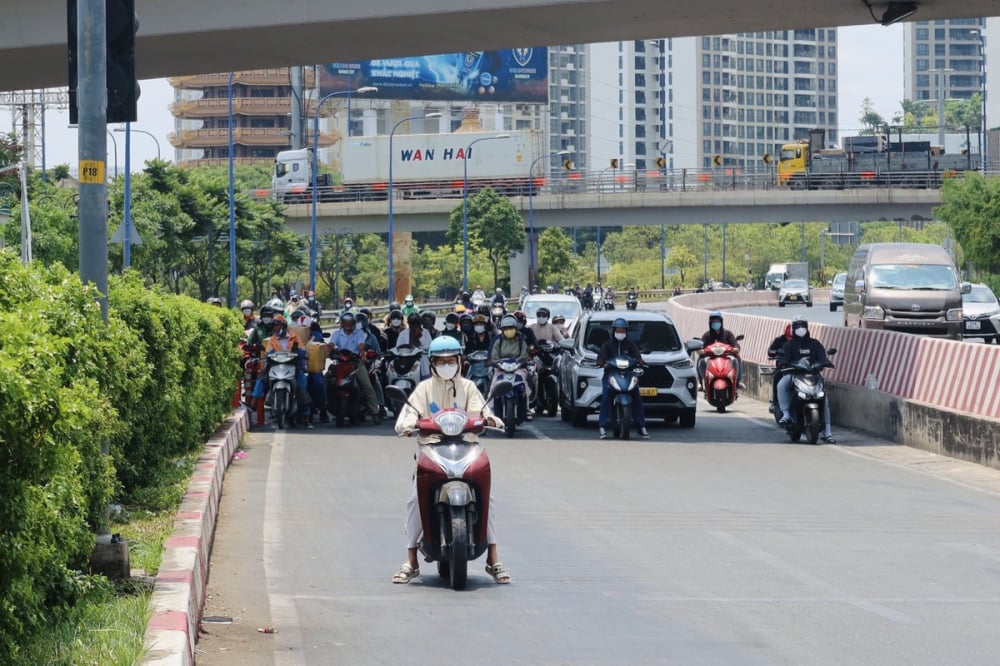 Nắng nóng khiến người đi đường tìm bóng mát để dừng đèn đỏ. Ảnh: Trần Minh

