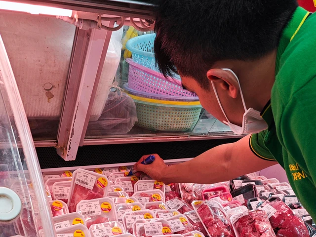 Các hệ thống bán lẻ đang giảm giá mạnh đối với sản phẩm thịt heo để kích cầu. Trong ảnh: Nhân viên siêu thị ghi giảm giá 40% sản phẩm thịt heo vào cuối ngày Ảnh: NGỌC ÁNH