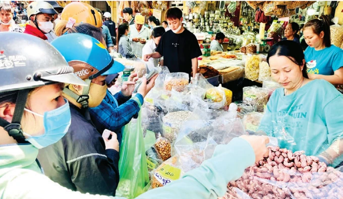 Khách chọn mua hạt điều, đồ khô các loại tại chợ Bình Tây (quận 6, TPHCM), chiều 28-1. Ảnh: GIA HÂN
