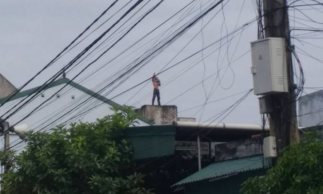 Người đàn ông ôm cháu bé đứng trên mái nhà.  