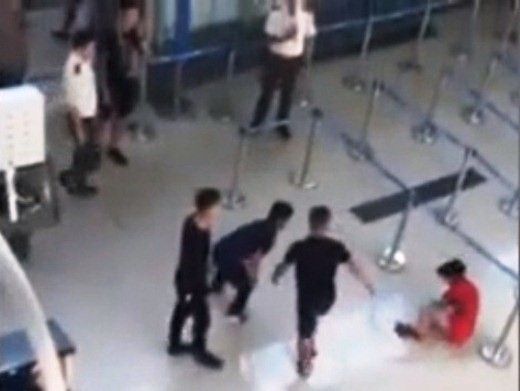 Các nhân viên an ninh hàng không (áo sáng màu) đã không can thiệp khi nữ nhân viên hãng Vietjet (áo đỏ) bị những người mặc quần áo sẫm màu hành hung - Ảnh cắt từ clip