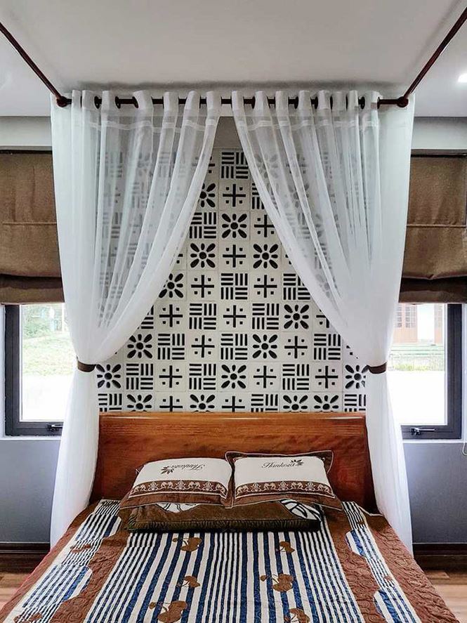 Phòng ngủ cũng được trang trí với gạch bông thông gió. Giường ngủ gỗ đơn giản về kiểu dáng nhưng vẫn nổi bật nhờ họa tiết trên chăn, gối, rèm ngủ trắng cho cảm nhận dễ chịu.  