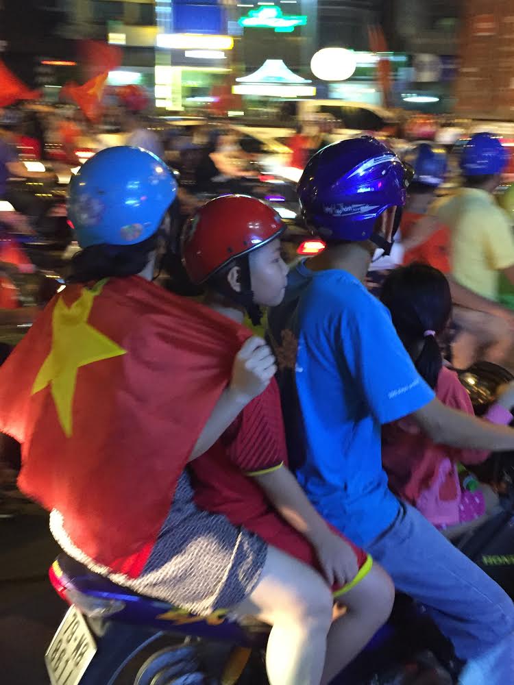 Cả gia đình mang theo lá cờ Tổ quốc ra đường chúc mừng Olympic Việt Nam